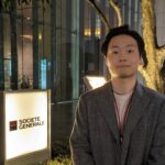iCLA graduate Takaaki stands in front of his workplace.