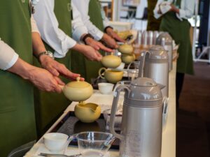 Instructors from the Japanese Tea Instructor Association hold traditional Japanese tea pots in a synchronized manner to brew tea. 