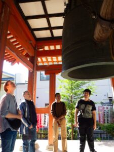 3 iCLA students and Professor William Reed look closely at the large bronze bell at Zenkoji Temple.