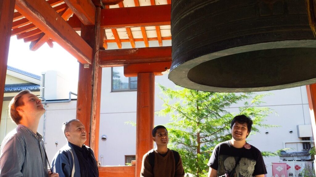 3 iCLA students and Professor William Reed look closely at the large bronze bell at Zenkoji Temple.