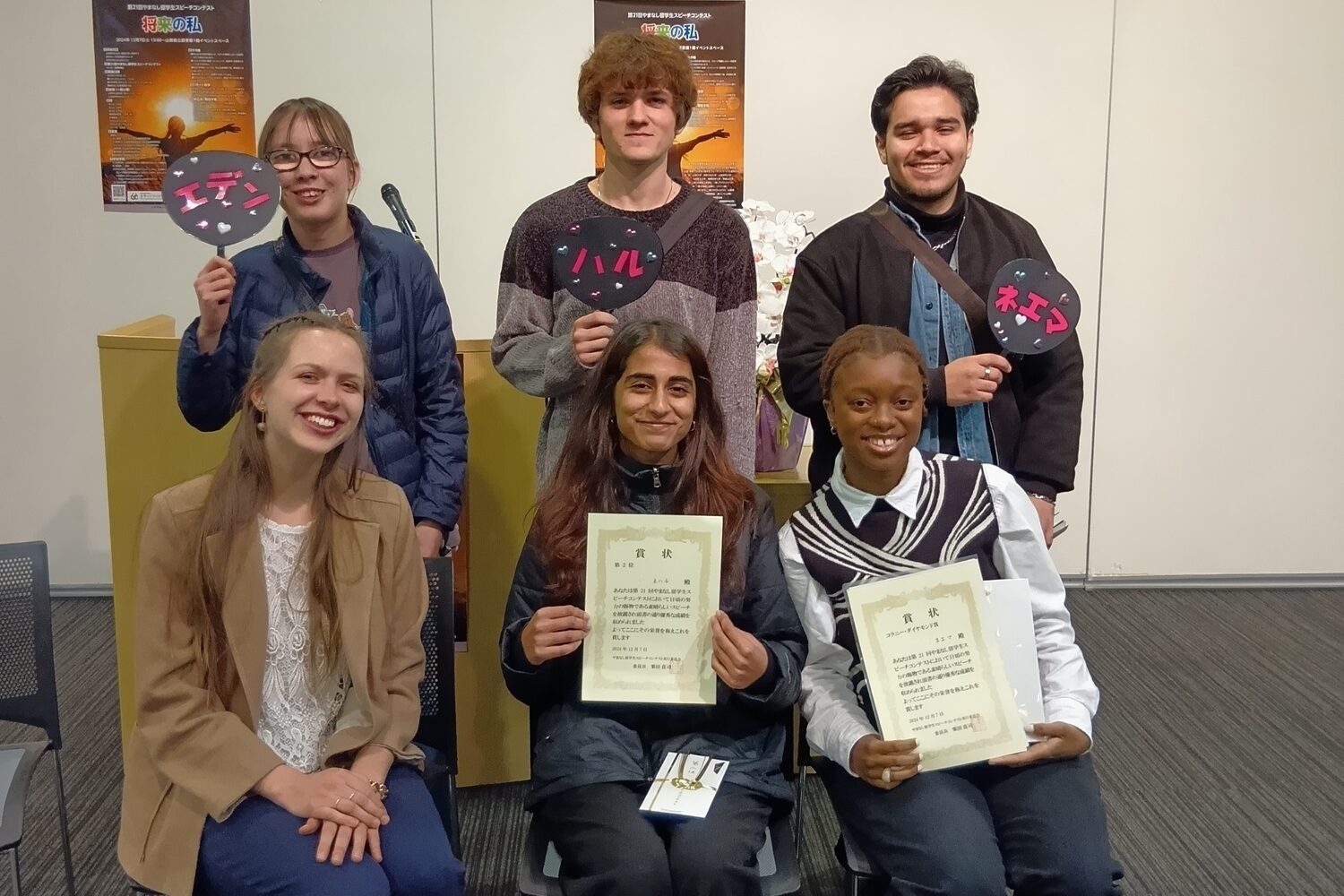 iCLA students who joined the Yamanashi International Student Speech Contest and their supporters pose for the camera. The students who won award are holding up their certificates. 