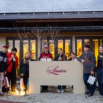 iCLA students stand around Lumiere Winery's sign, where they learned about wine making in Yamanashi.